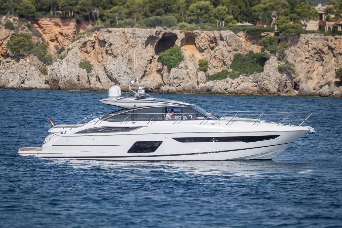 2016 Princess V58 Open yacht cruising near rocky coastline.
