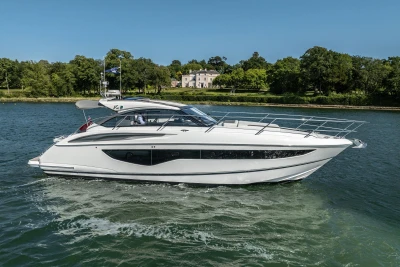 2024 Princess V40 yacht cruising on a serene lake with lush greenery in the background.
