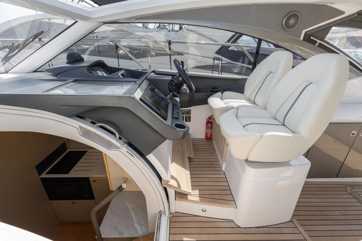 Interior of 2018 Princess V40 yacht with helm, white seats, and wooden flooring.