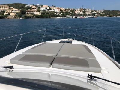 2022 Princess V40 yacht with sunbathing deck, cruising near coastal homes and marina.