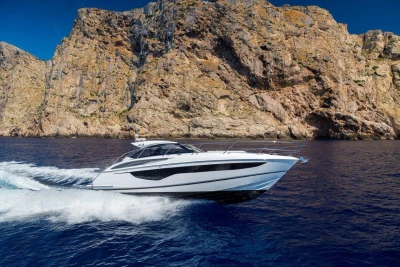 2022 Princess V40 yacht cruising near rocky cliffs on a clear blue sea.