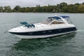 2000 Princess V42 yacht cruising on a serene lake with lush green shoreline.