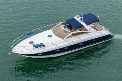 2000 Princess V42 yacht cruising on calm green waters, featuring sleek design and blue canopy.