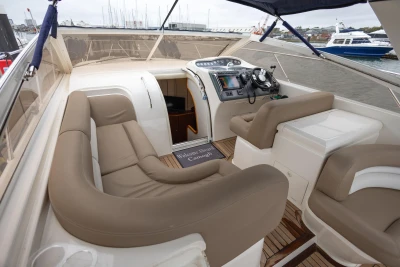Luxurious interior of 2000 Princess V42 yacht with beige seating and modern controls.