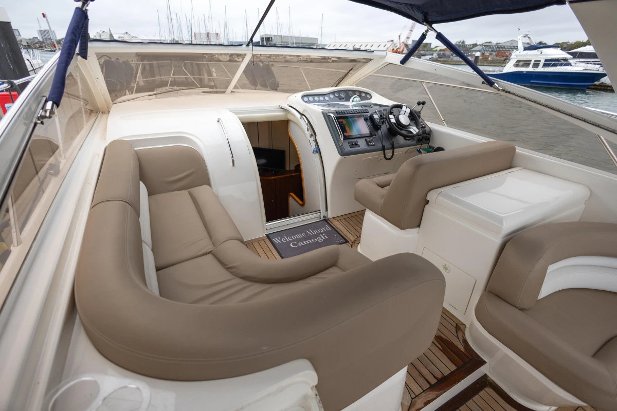 Luxurious interior of 2000 Princess V42 yacht with beige seating and modern controls.