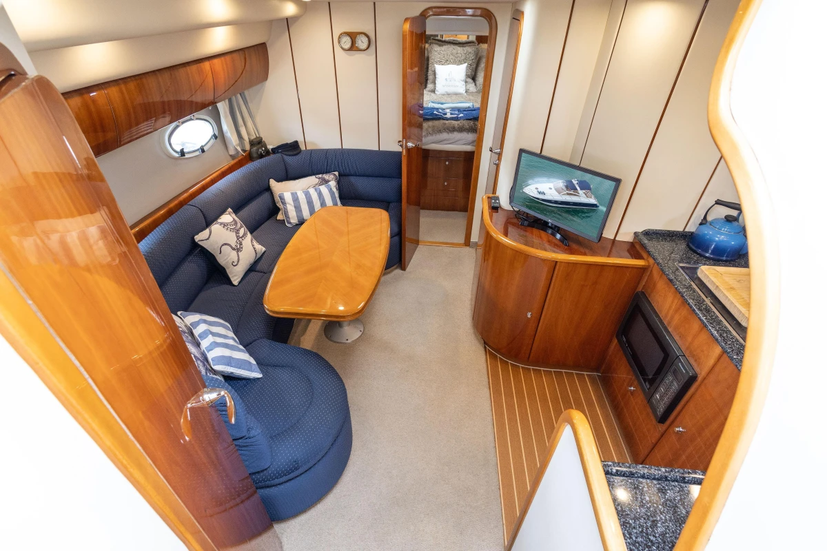 Luxurious interior of 2000 Princess V42 yacht with cozy seating, TV, and kitchenette.