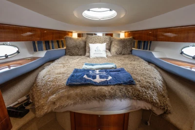 Luxurious cabin interior of 2000 Princess V42 yacht with plush bedding and elegant wood finishes.