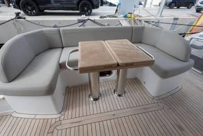 Luxurious seating area on 2023 Princess F55 yacht with wooden table and cushioned benches.