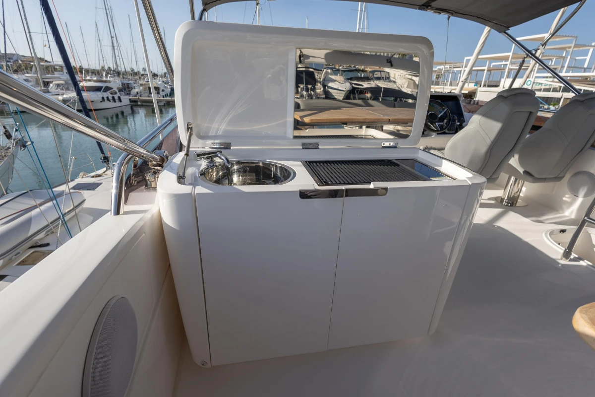 Outdoor kitchenette on 2023 Princess F50 yacht, featuring sink and grill, docked at marina.