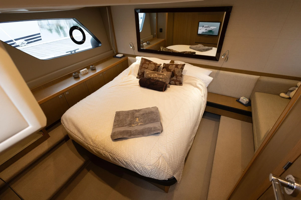 Luxurious cabin interior of 2014 Princess V52 yacht with cozy bed and elegant decor.