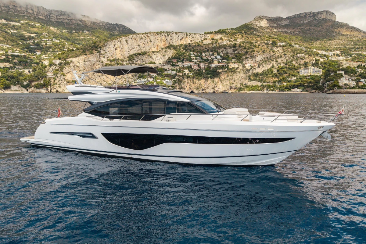 Luxurious 2022 Princess S78 yacht cruising near scenic coastal cliffs.