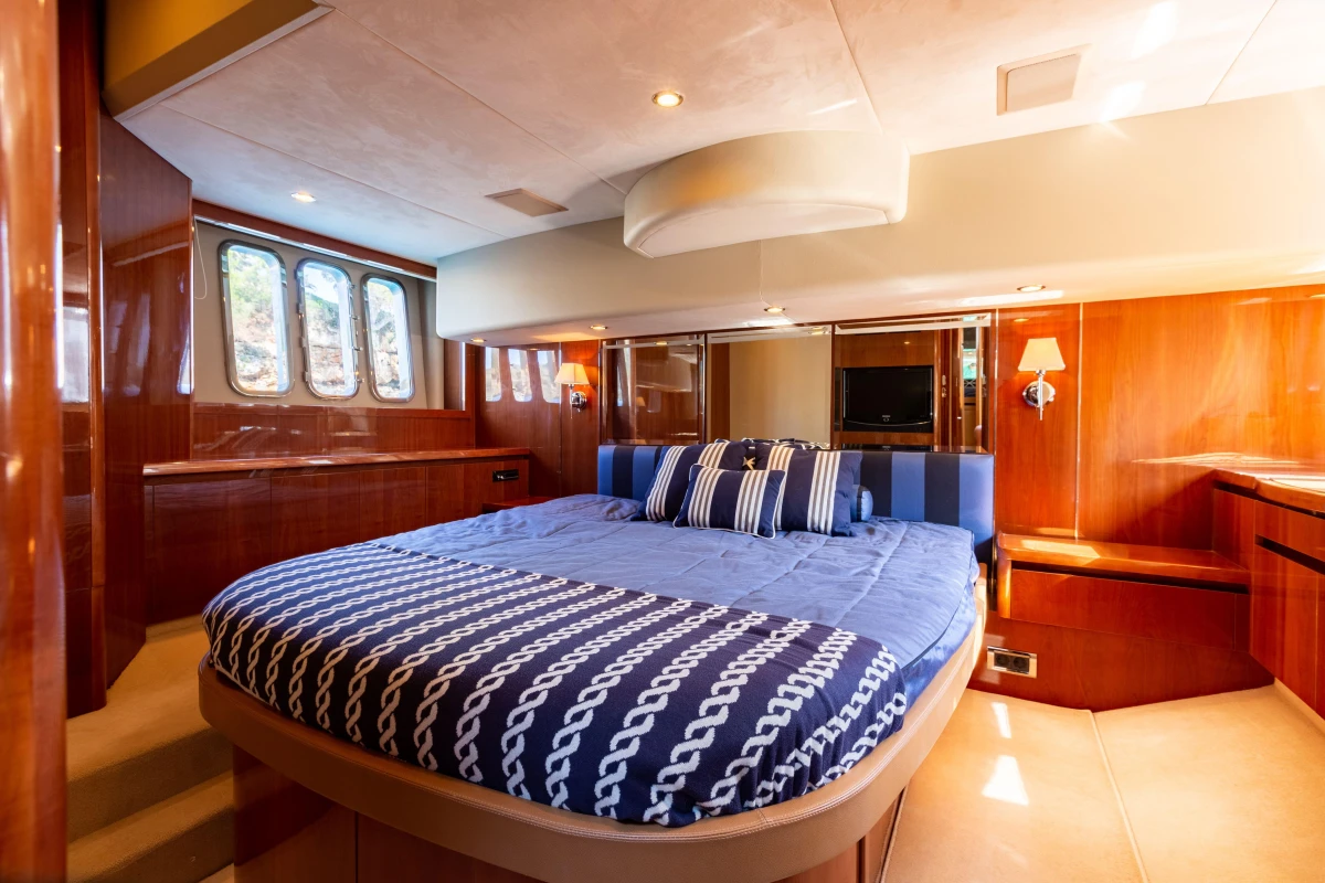 Luxurious bedroom interior of 2008 Princess 58 yacht with elegant wood paneling and nautical bedding.