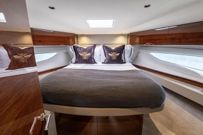 Luxurious 2023 Princess V50 yacht cabin with elegant bedding and wood accents.