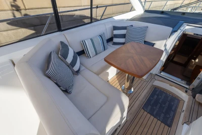 Luxurious seating area on 2006 Princess V53 yacht with striped cushions and wooden table.