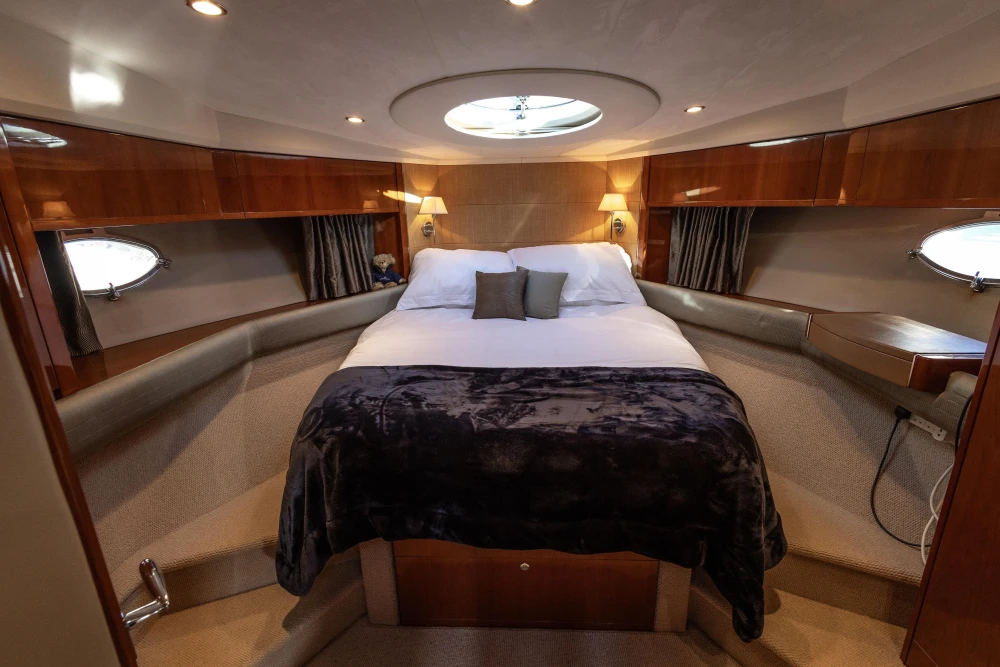 Luxurious cabin interior of 2006 Princess V53 yacht with cozy bed and elegant lighting.