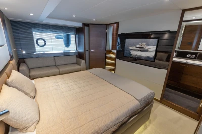 Luxurious bedroom interior of 2015 Princess 68 yacht with modern decor and large TV.
