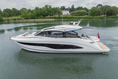 2025 Princess V55 yacht cruising on a serene lake with lush greenery.