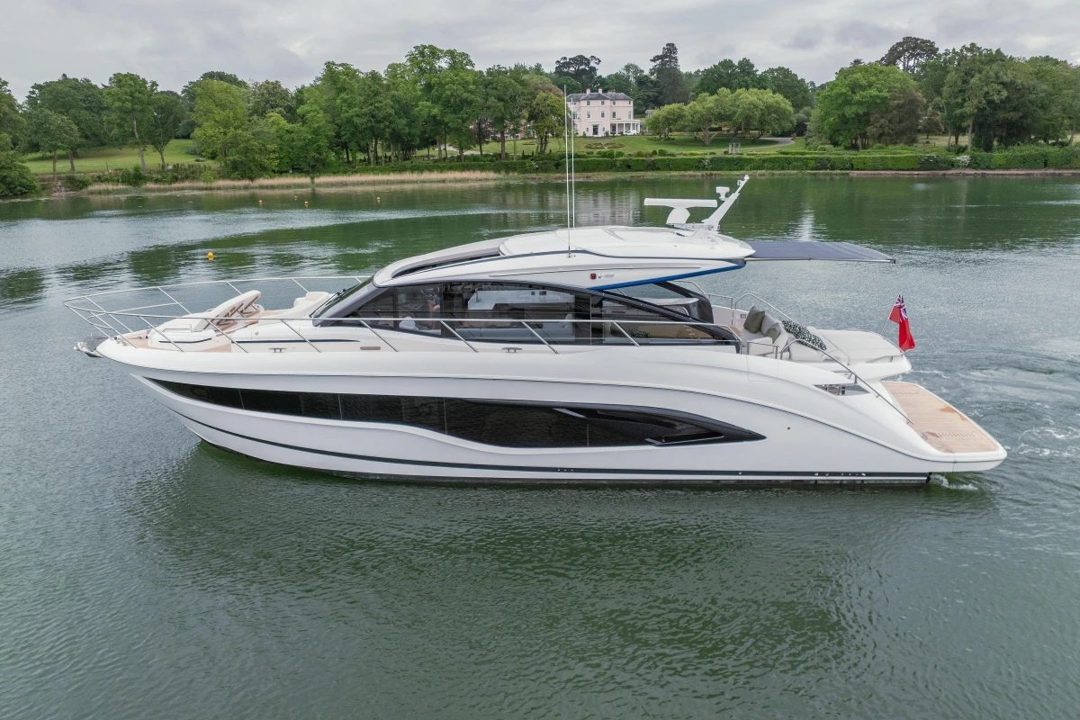 2025 Princess V55 yacht cruising on a serene lake with lush greenery.