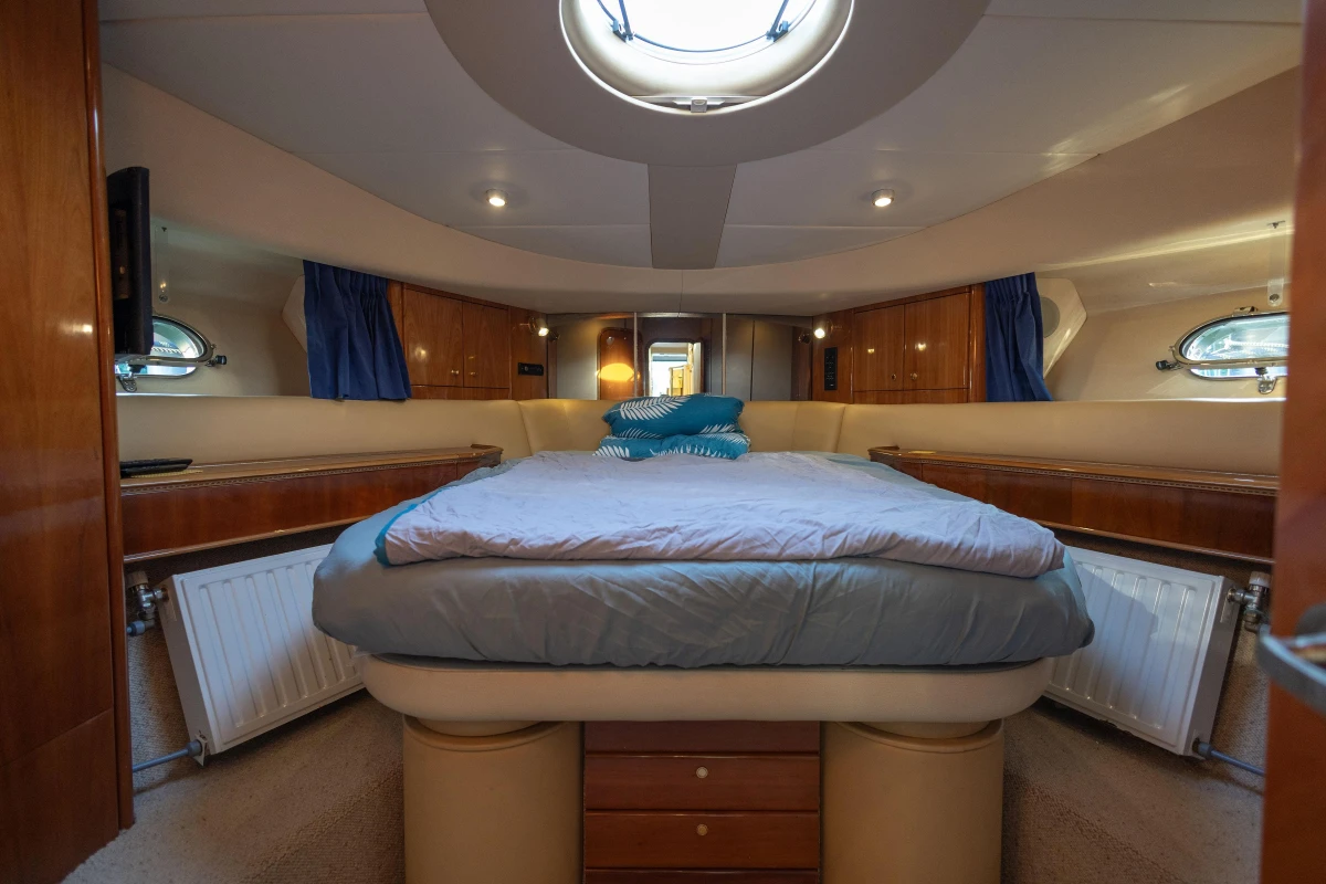 Luxurious cabin interior of a 1995 Princess 60 yacht with cozy bedding and elegant wood finishes.