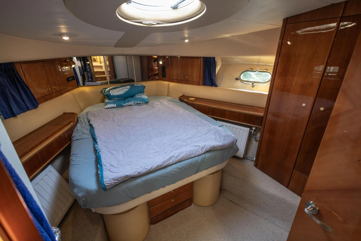 Luxurious cabin interior of a 1995 Princess 60 yacht with cozy bed and wooden furnishings.