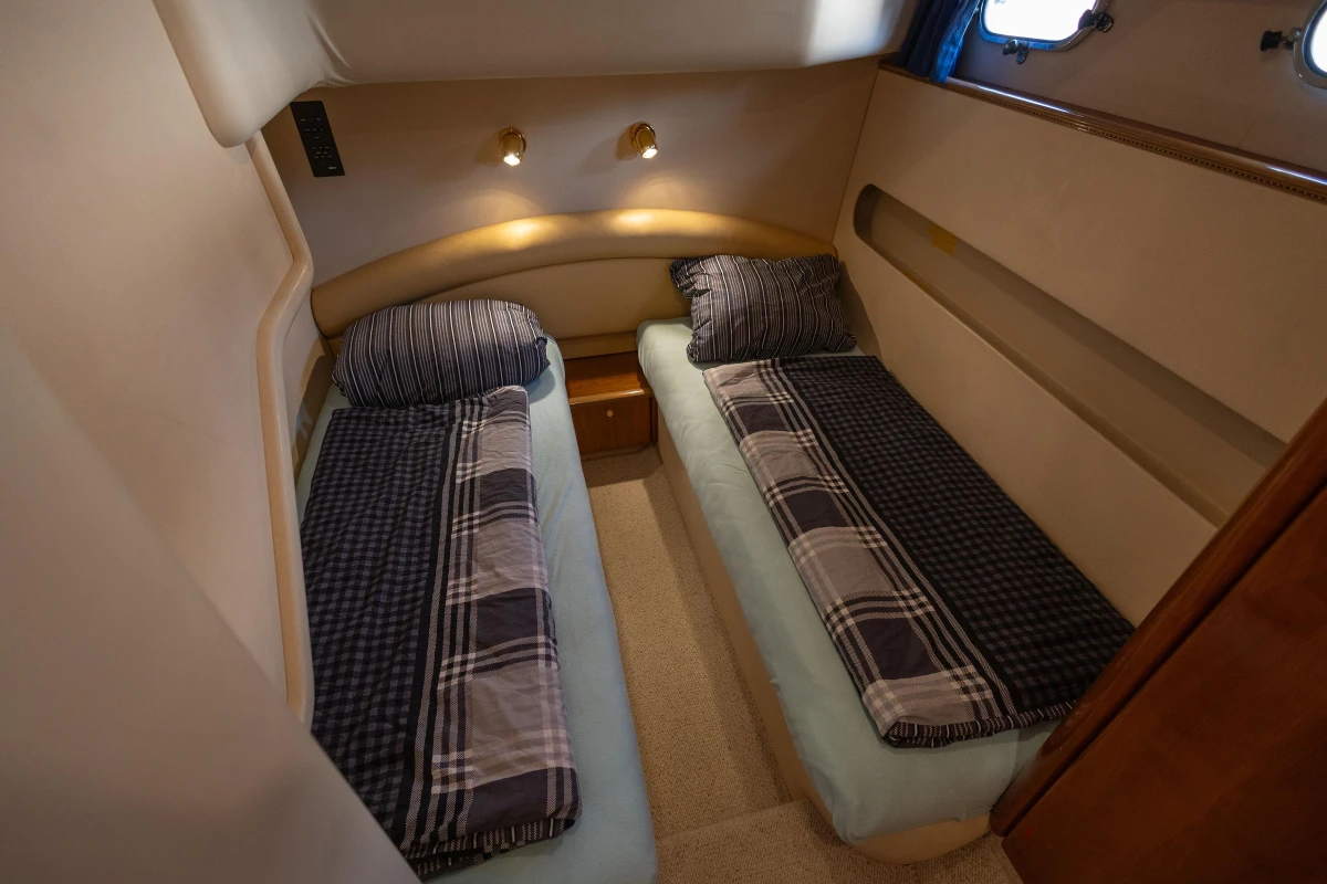 Twin cabin interior of 1995 Princess 60 yacht with plaid bedding and soft lighting.