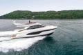 2023 Princess F45 yacht cruising on open water near a lush green coastline.