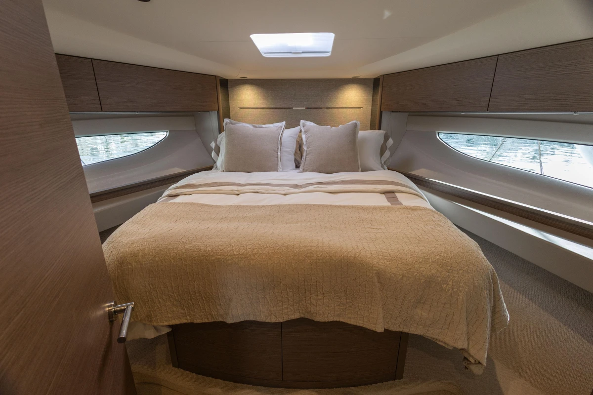 Luxurious bedroom interior of 2023 Princess V50 Open yacht with elegant bedding and wood accents.