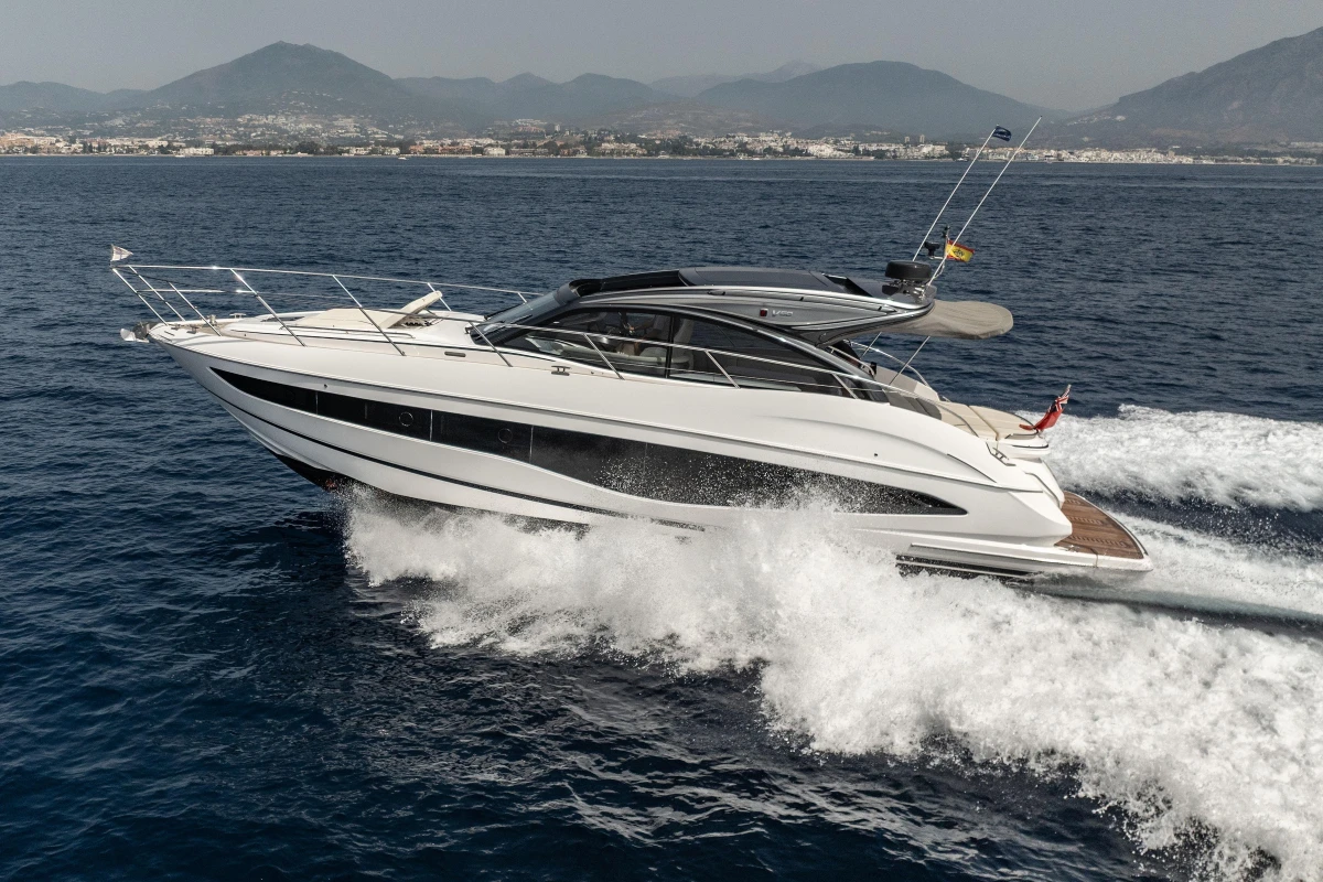 2023 Princess V50 Open yacht cruising on the ocean with scenic mountain backdrop.