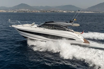 2023 Princess V50 Open yacht cruising on the ocean with scenic mountain backdrop.