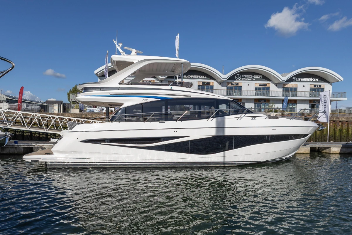2025 Princess F58 yacht docked at marina, clear sky, modern architecture in background.